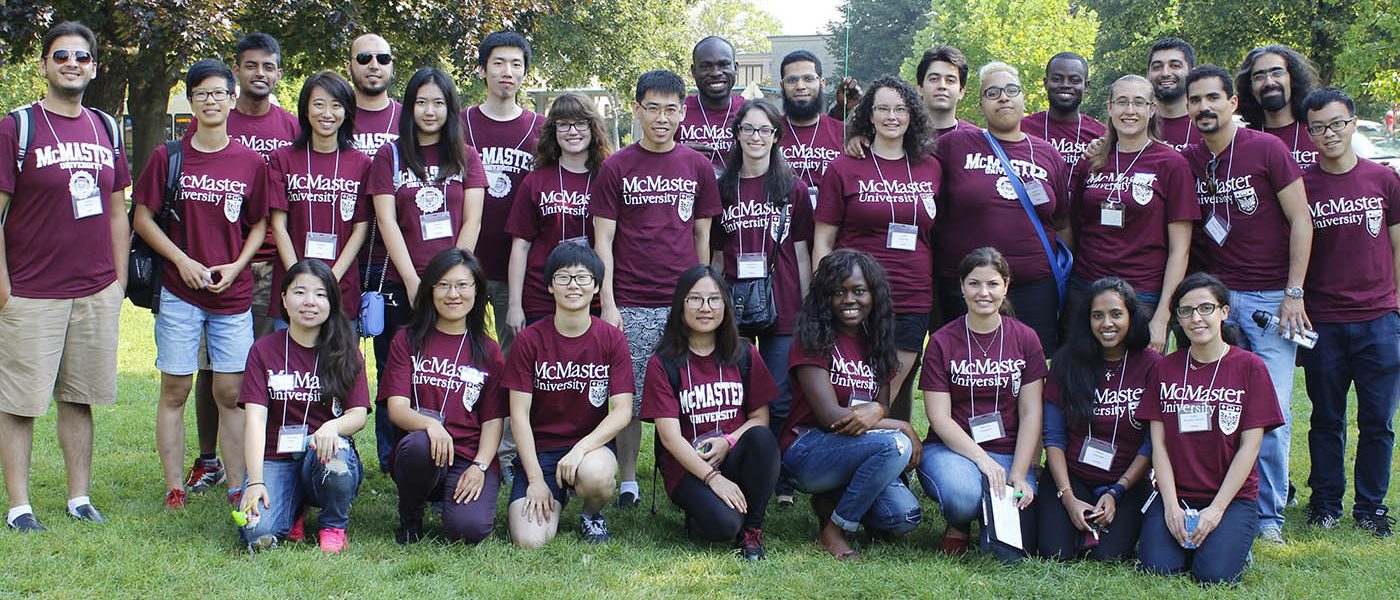 A group of graduate students pose in rows. Each are wearing a McMaster Unversity volunteer t-shirt.