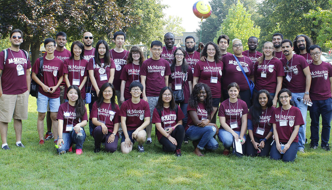 A group of graduate students pose in rows. Each are wearing a McMaster Unversity volunteer t-shirt.