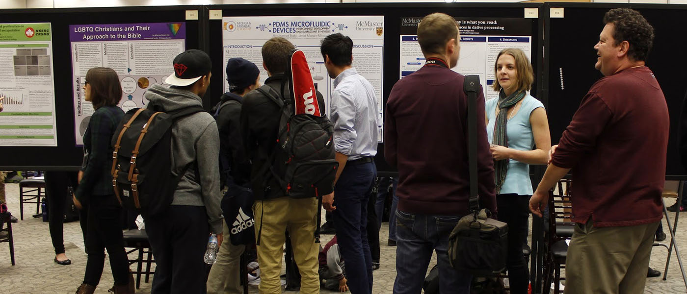 McMaster students and faculty chat in front of poster boards in CIBC Hall during a USRA poster session