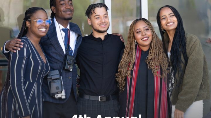 Five black students smile as they stand side-by-side, with their arms around each others backs.